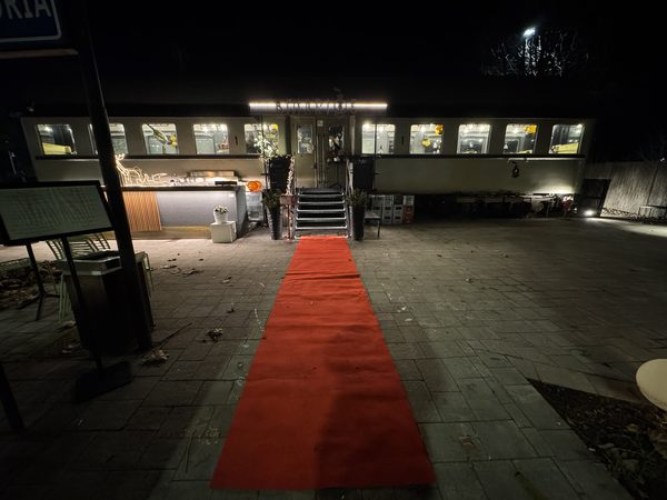 La carrozza di notte vista di fronte, con il tappeto rosso steso fino alla scala d'ingresso