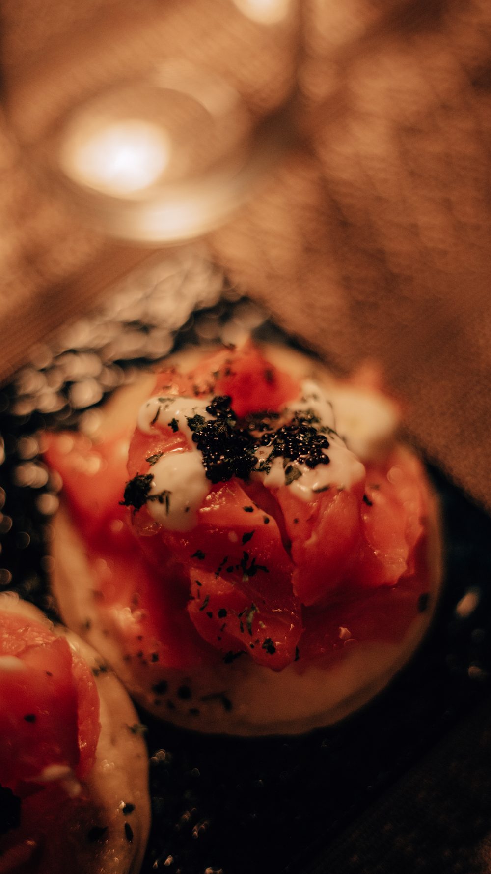 Blinis con salmone marinato, panna acida e caviale, fotografato da vicino sotto la luce calda del vagone